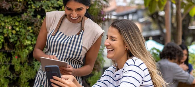 To damer som ser på en telefon